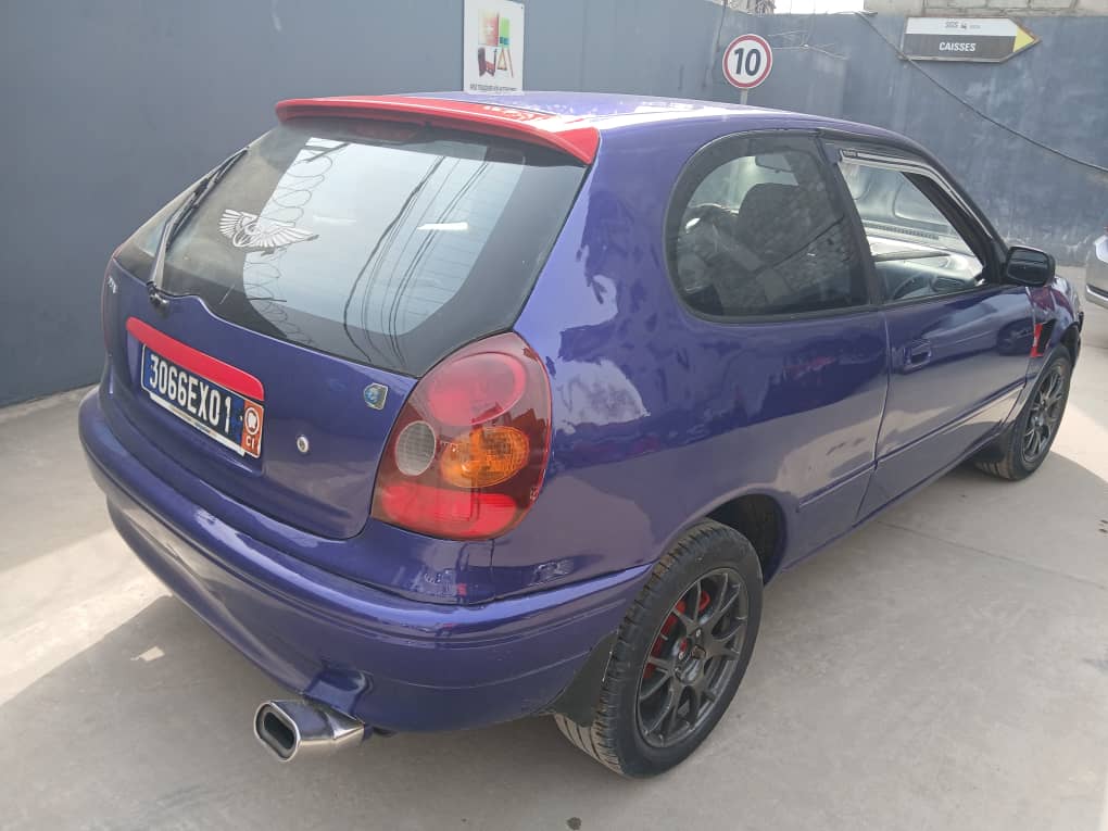 Toyota Etio Compact bleu violet brillant photographiée de face en extérieur, carrosserie propre et sans rayure, phares avant et calandre bien visibles.